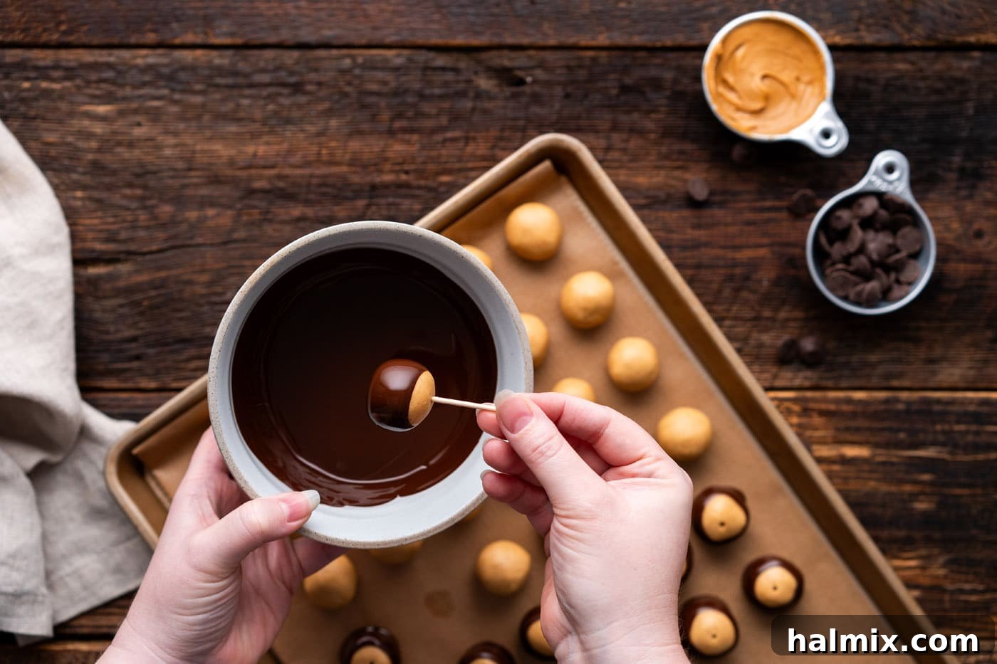 dipping buckeye candy into melted chocolate with a toothpick