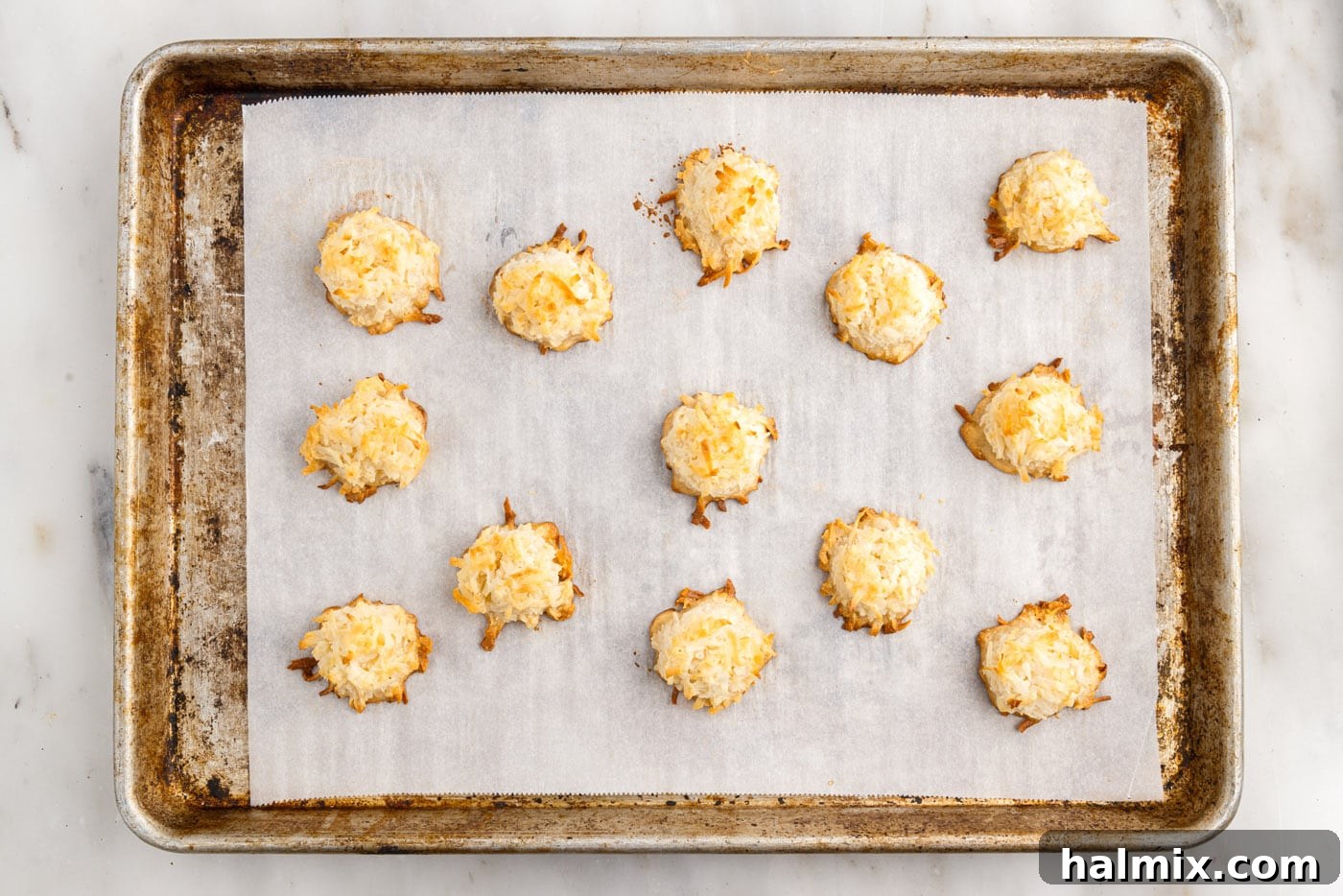 Easy baked coconut macaroons fresh out of the oven, exhibiting a perfect golden-brown color on a cookie sheet.