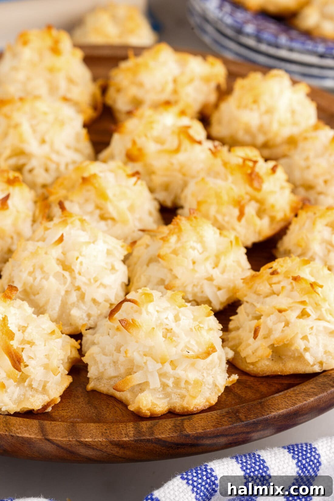 A generous pile of perfectly golden and chewy coconut macaroons artfully arranged on a wooden platter, inviting you to grab one and enjoy.