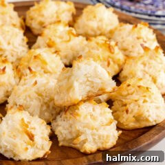 Coconut Macaroons on a wooden platter with a bite taken out of one, showcasing their delightful texture and golden-brown perfection.