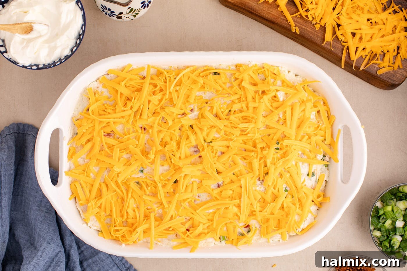 Decadent Twice Baked Potato Casserole 12 A close-up of shredded cheddar cheese sprinkled abundantly over the mashed potato casserole, preparing it for its final bake.