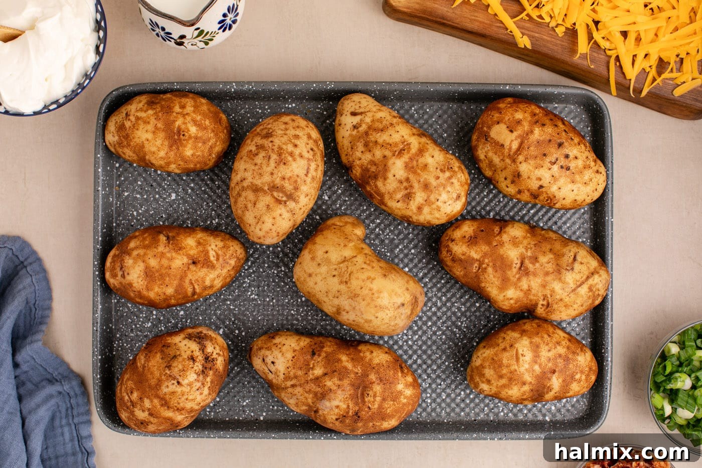 Decadent Twice Baked Potato Casserole 5 Russet potatoes with fork piercings ready for baking on a baking sheet.