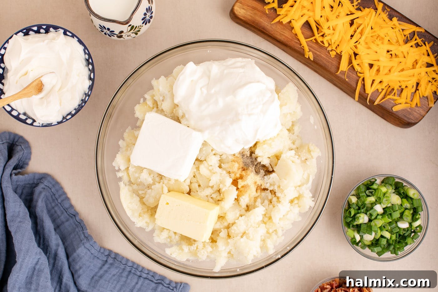 Decadent Twice Baked Potato Casserole 7 Sour cream, cream cheese, milk, butter, garlic powder, and ground pepper added to the mashed potatoes in a large mixing bowl, ready to be combined.