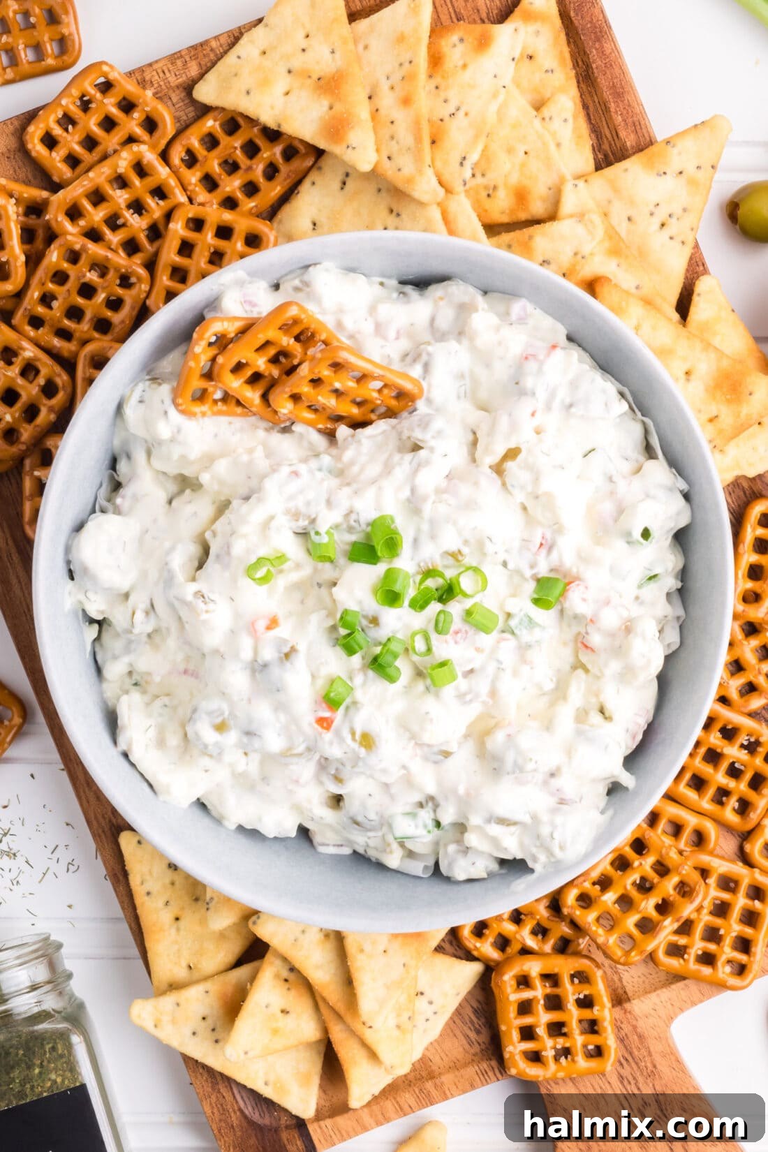 Overhead photo of a bowl of Dirty Martini Dip, garnished with olives and a sprig of rosemary