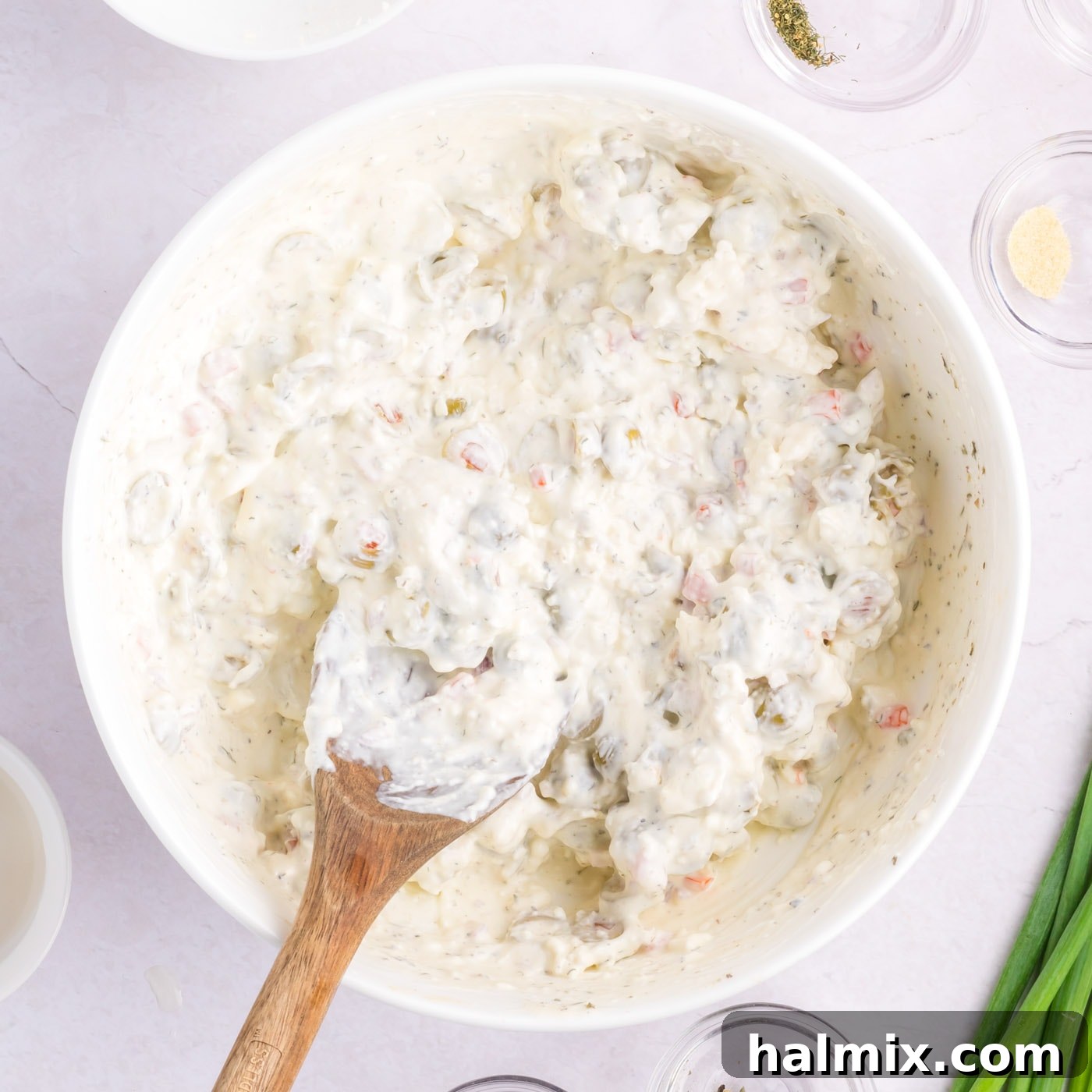 mixing dirty martini dip with a wooden spoon