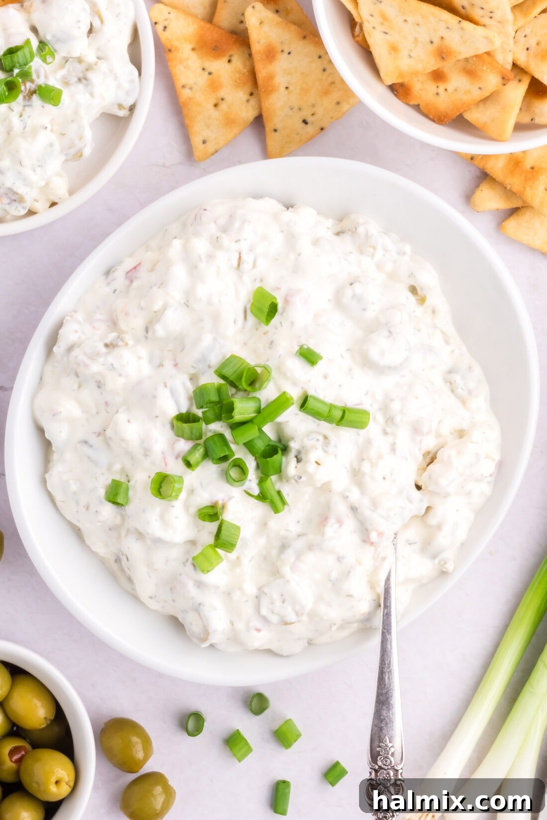 Bowl of Dirty Martini Dip with crackers and olives on the side, ready for dipping