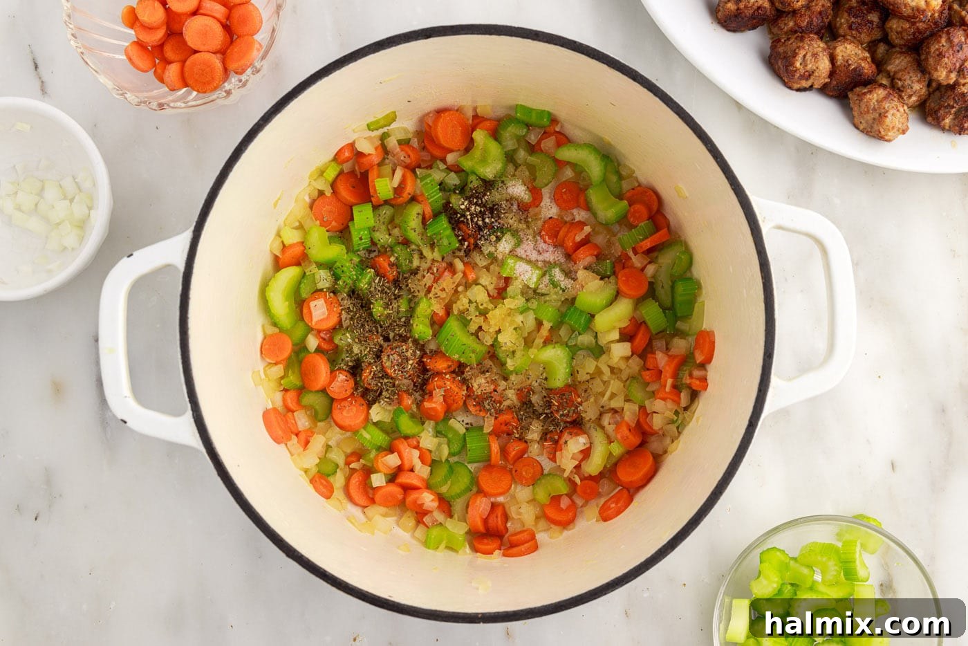 seasoning sprinkled over carrots, celery, and onion in a soup pot
