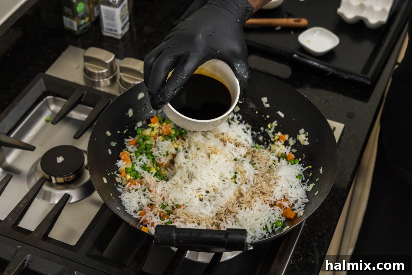 pouring soy sauce into wok with rice and vegetables