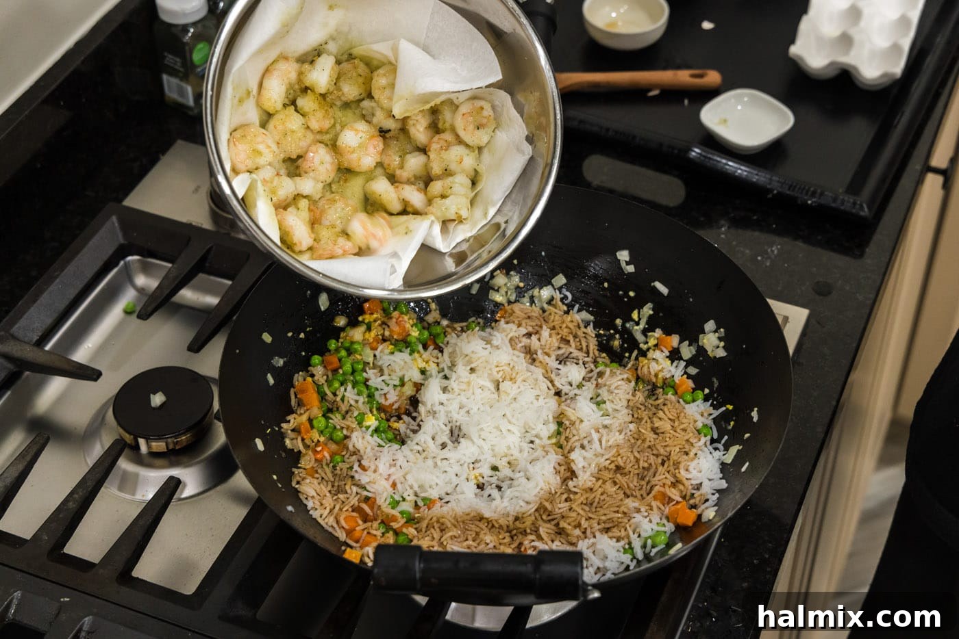 adding cooked shrimp to wok with fried rice and vegetables