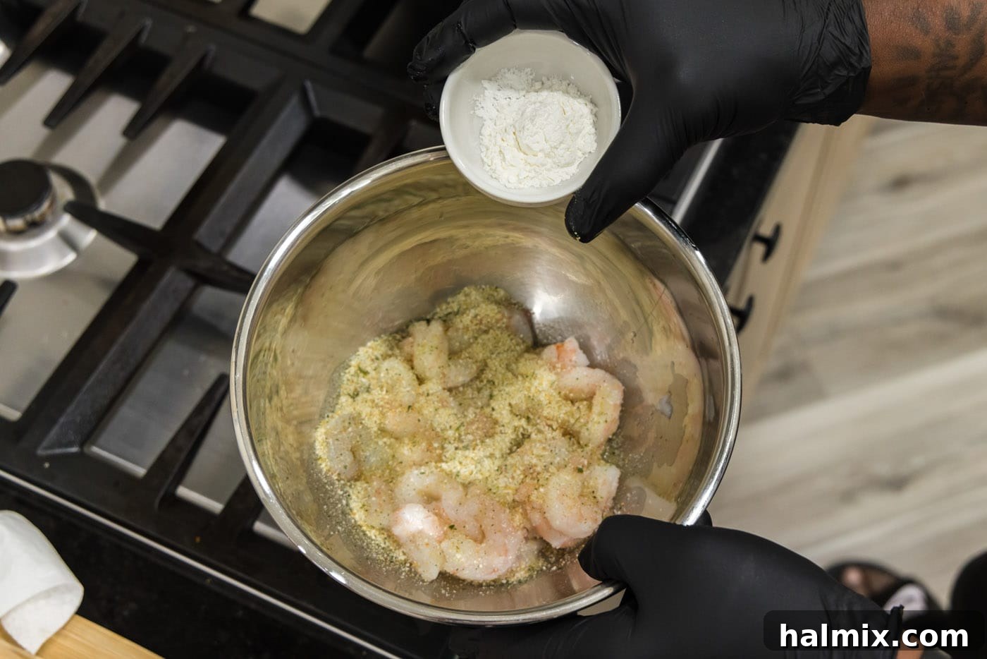 adding cornstarch to bowl with seasoned shrimp
