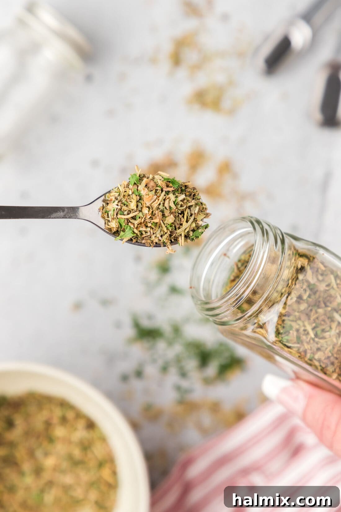 Spoonful of Italian Seasoning pulled out of a seasoning jar, showcasing the rich blend of herbs