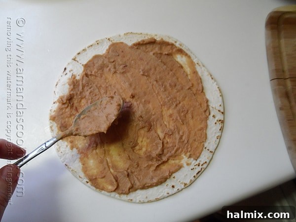 An overhead shot showcasing a tortilla with creamy refried beans spread evenly across its surface.