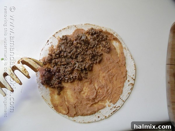 A tortilla generously spread with refried beans, topped with a savory layer of seasoned ground beef.