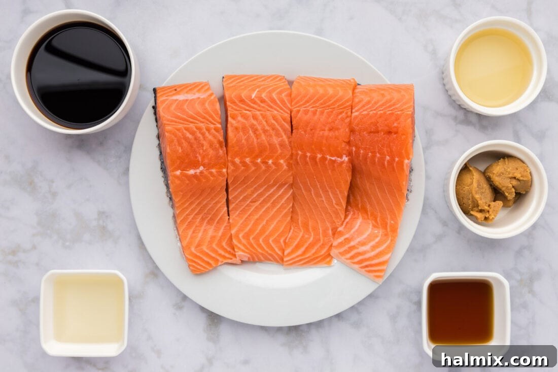 Various fresh ingredients laid out for Miso Salmon preparation, including salmon fillets, miso paste, soy sauce, sesame oil, sake, rice vinegar, cornstarch, and water.