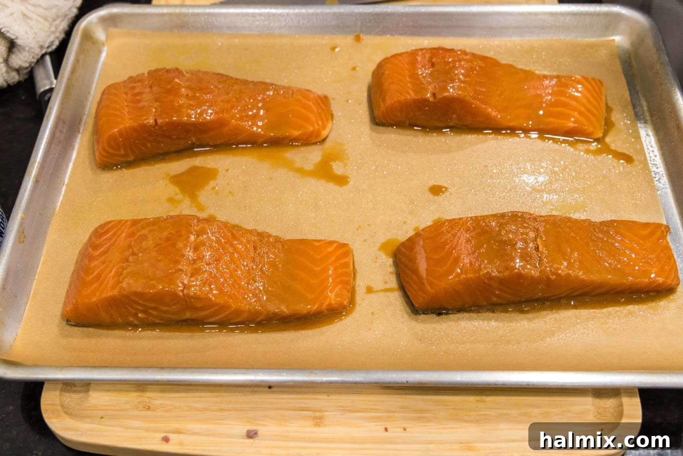 Arranging marinated miso salmon fillets, skin-side down, on a baking sheet lined with parchment paper.
