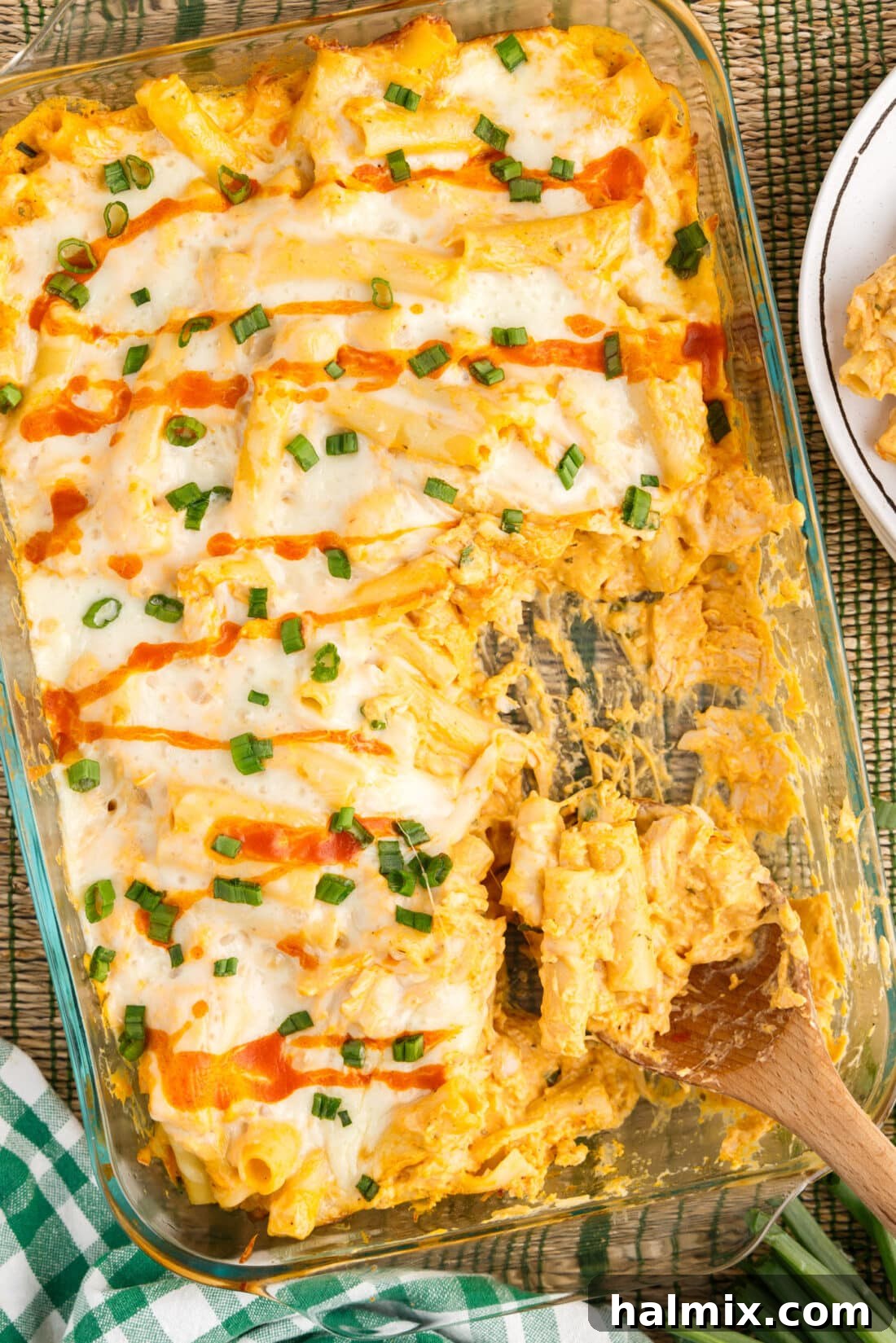 Dish of Buffalo Chicken Casserole with a spoon in it, showcasing its creamy texture and bubbly cheese topping.
