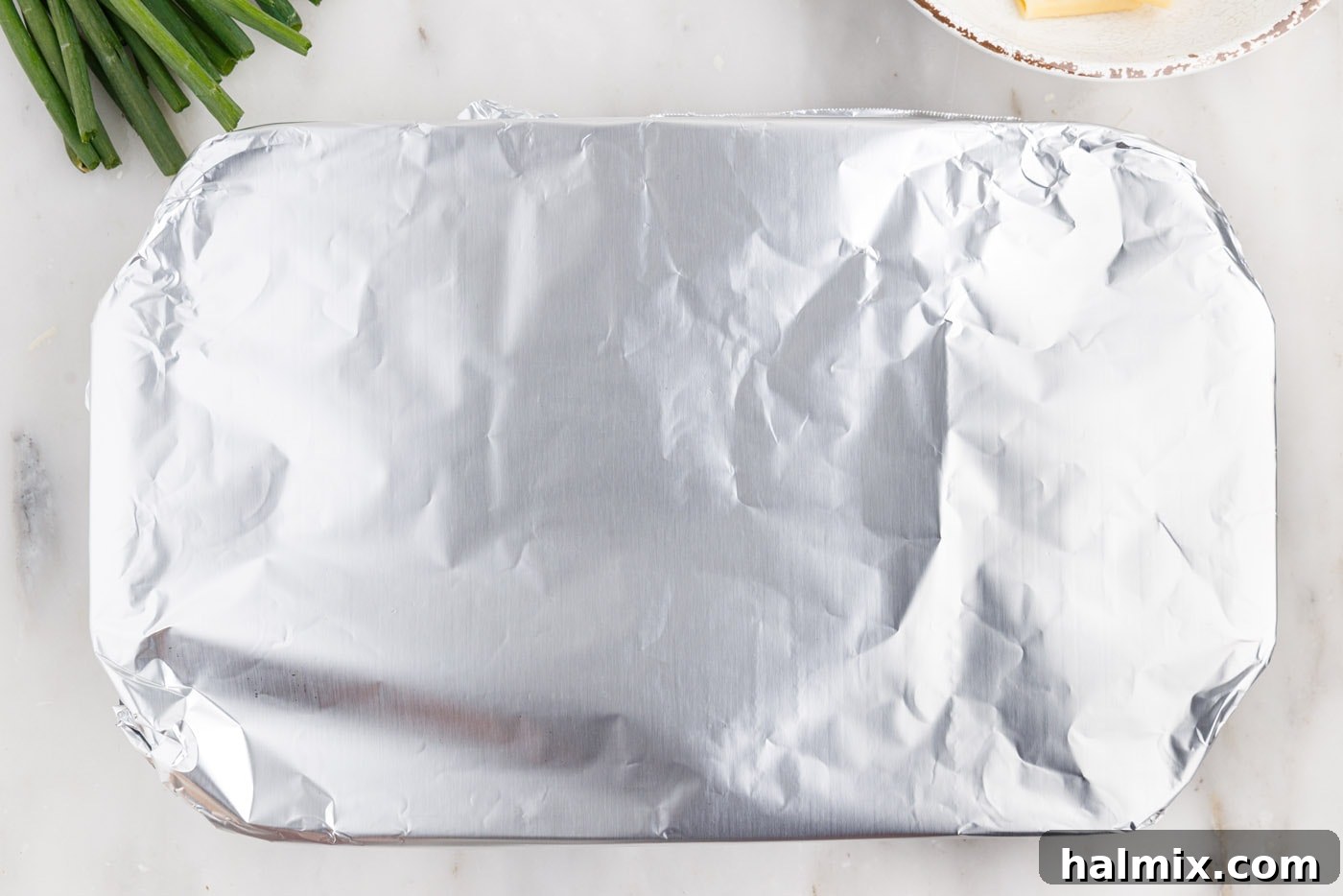 Aluminum foil covering the buffalo chicken casserole in the baking dish before it goes into the oven.