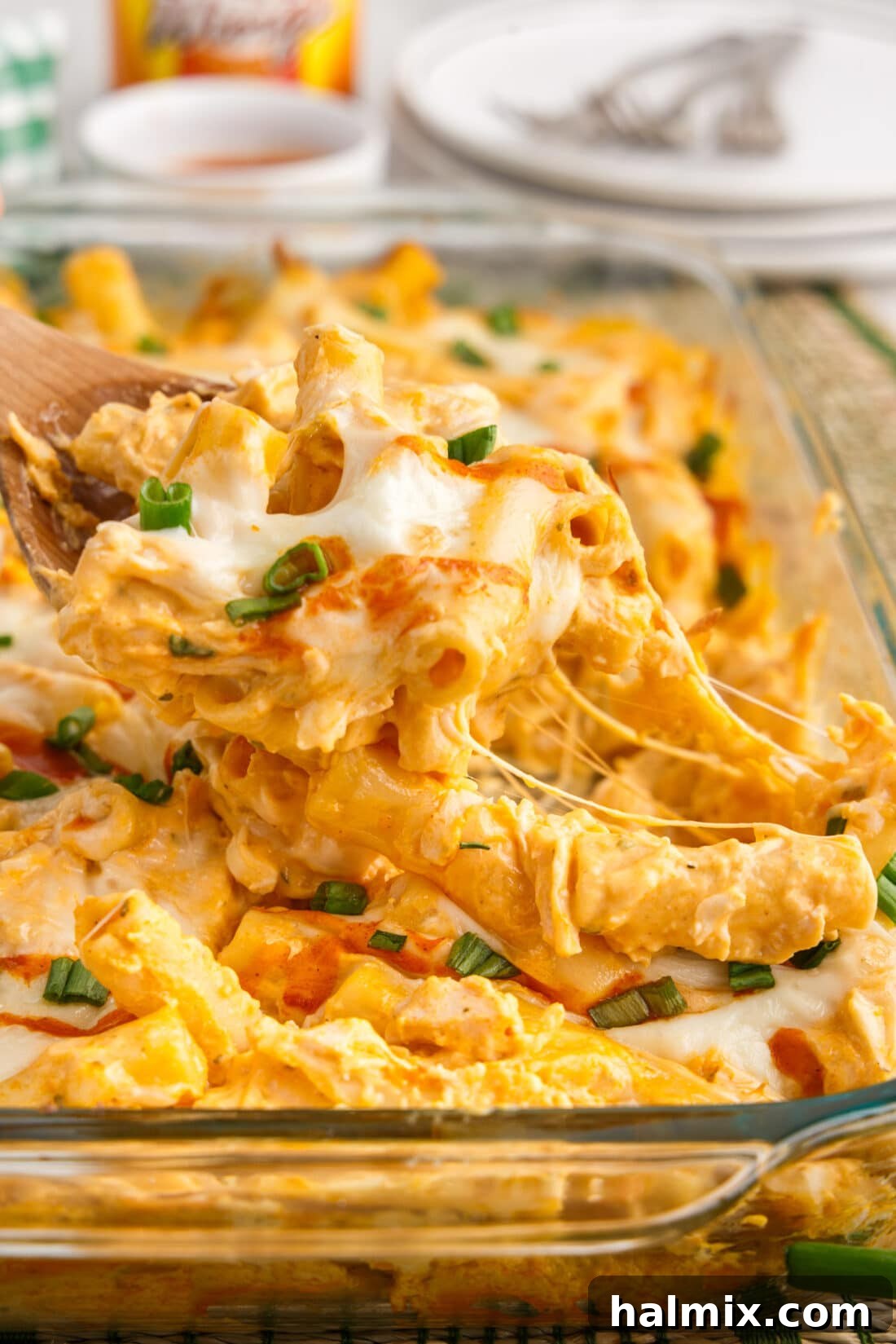 A spoonful of Buffalo Chicken Casserole being lifted out of the dish, showing the molten cheese and chicken.