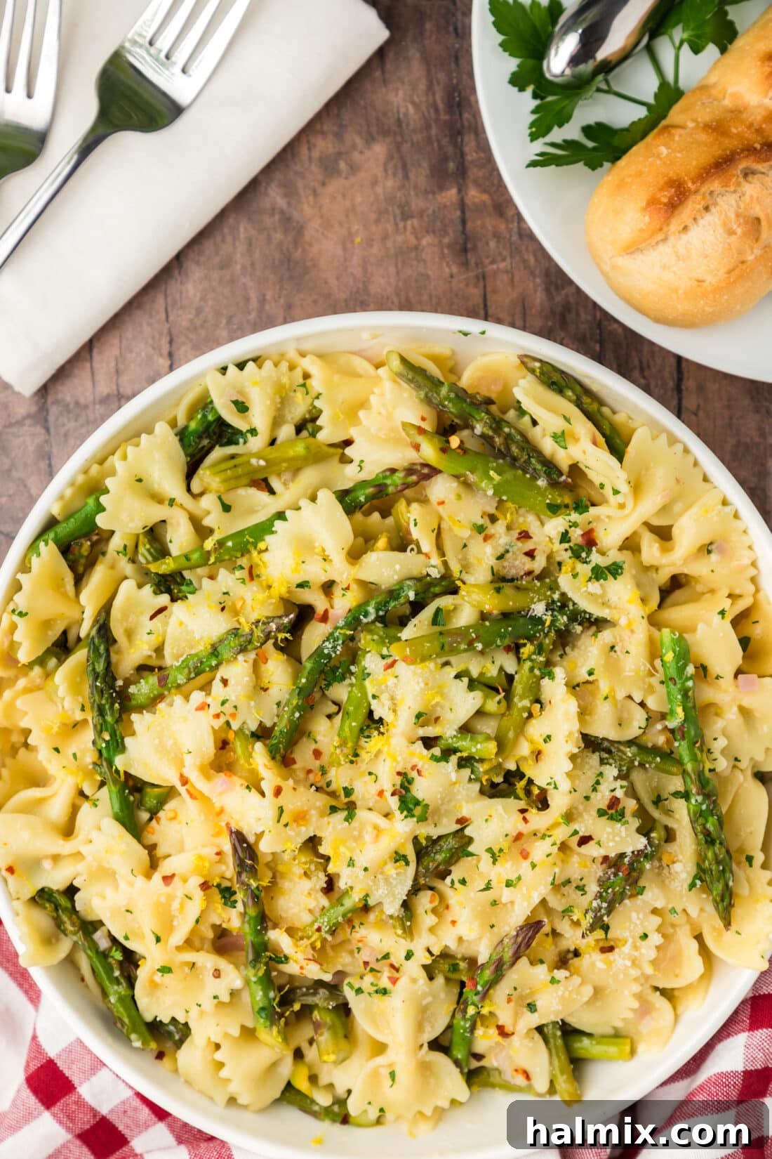 A vibrant bowl of Asparagus Pasta served with crusty bread on the side, showcasing the tender green asparagus and golden bowtie pasta.