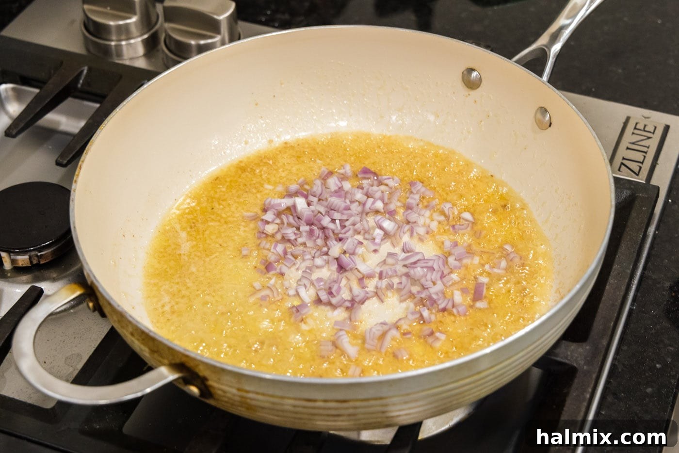 Melted butter in a skillet with minced garlic and shallots beginning to soften and become fragrant.