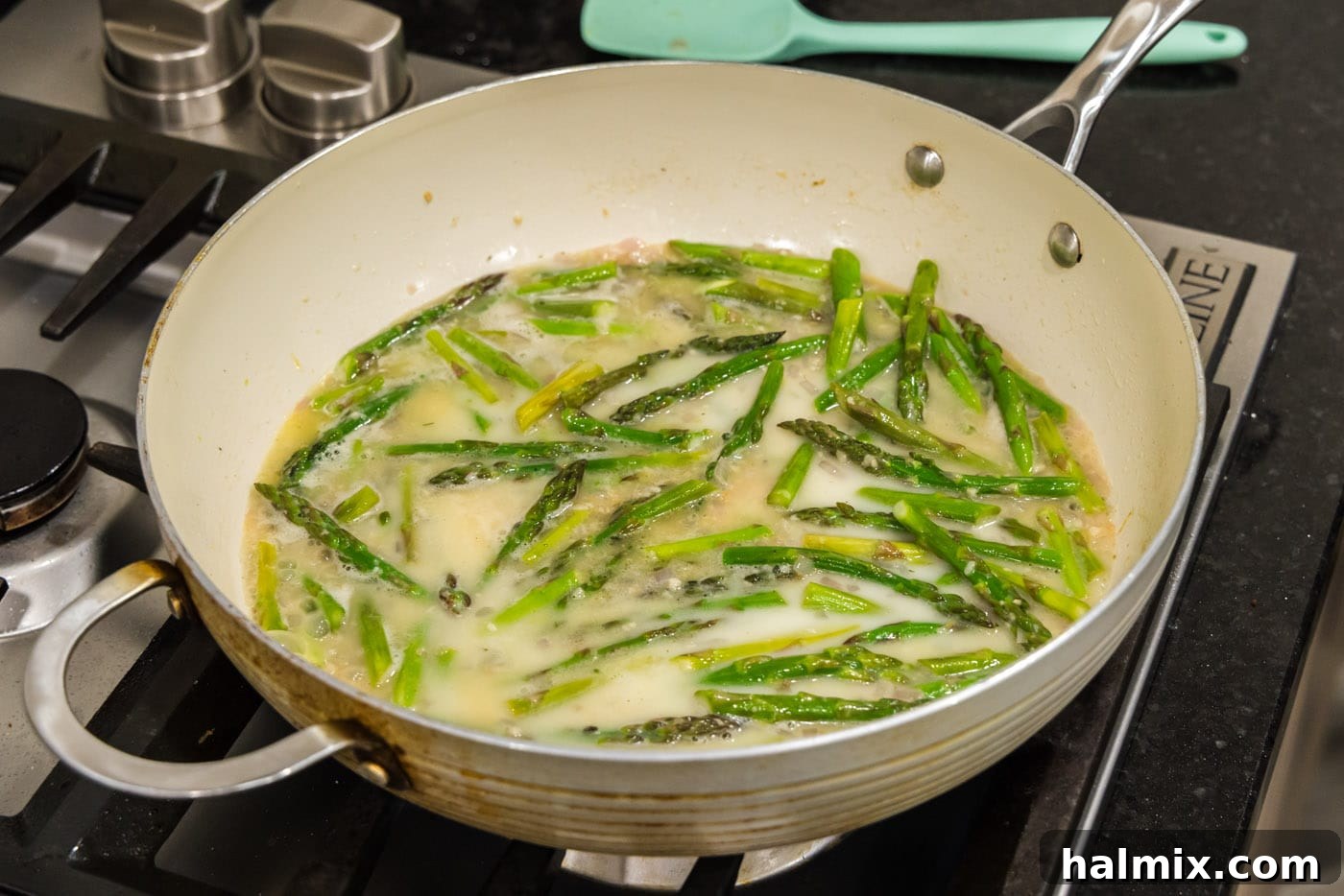 Cornstarch slurry being added to the asparagus pasta sauce in the skillet, beginning to thicken the sauce.