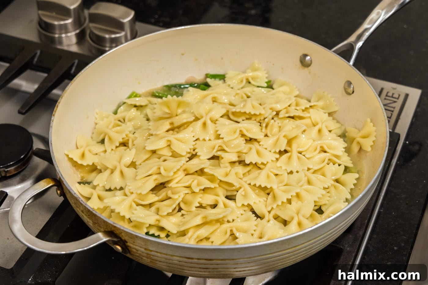 Cooked bowtie pasta added to the skillet with the buttered asparagus sauce, ready to be tossed.