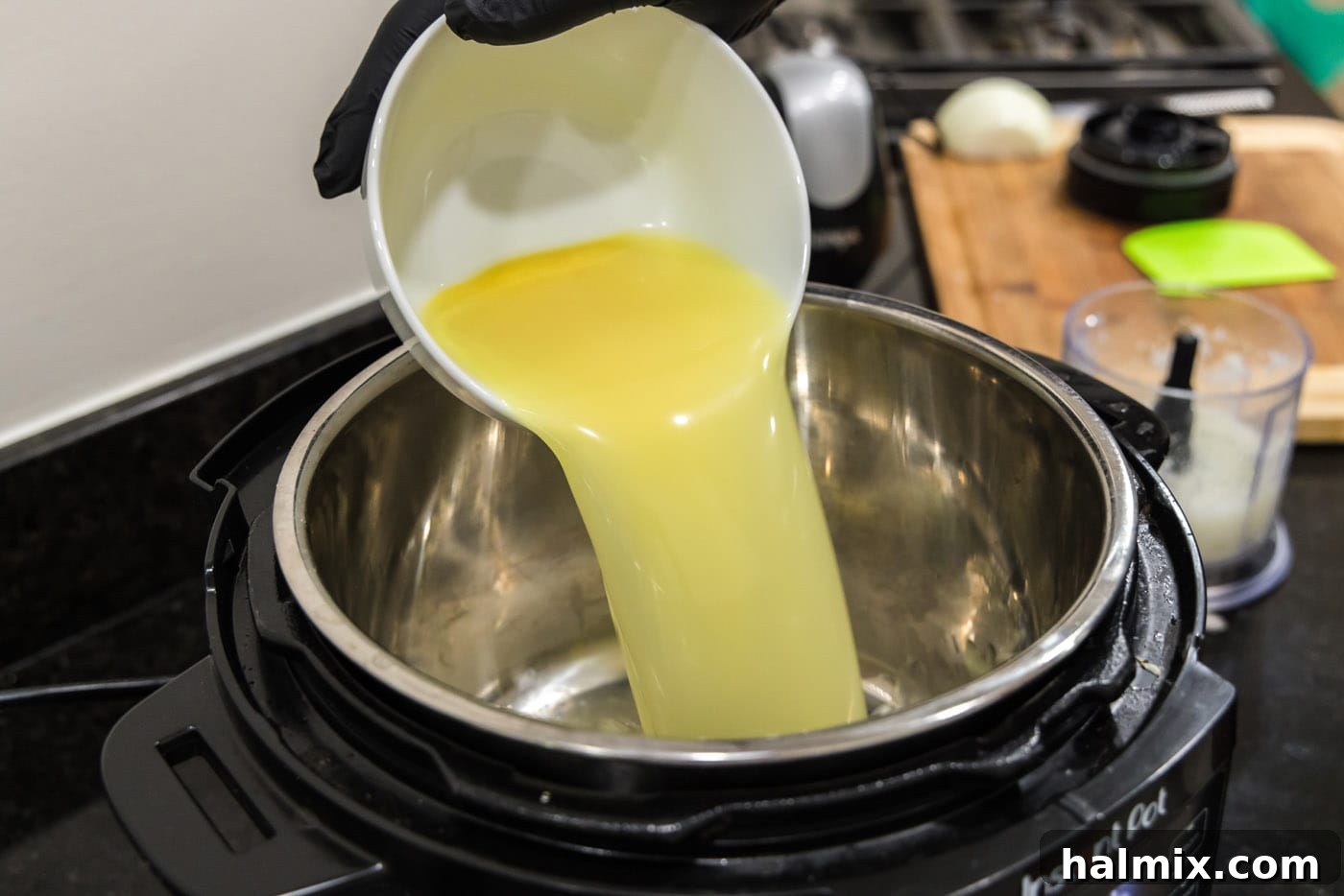 Pouring chicken stock directly into the Instant Pot's inner pot.