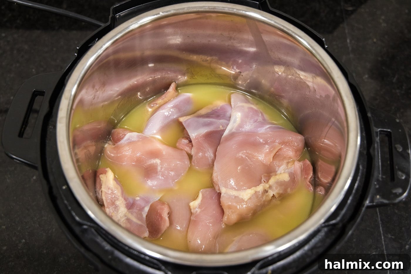 Boneless, skinless chicken breasts and thighs settled in the Instant Pot with chicken stock.