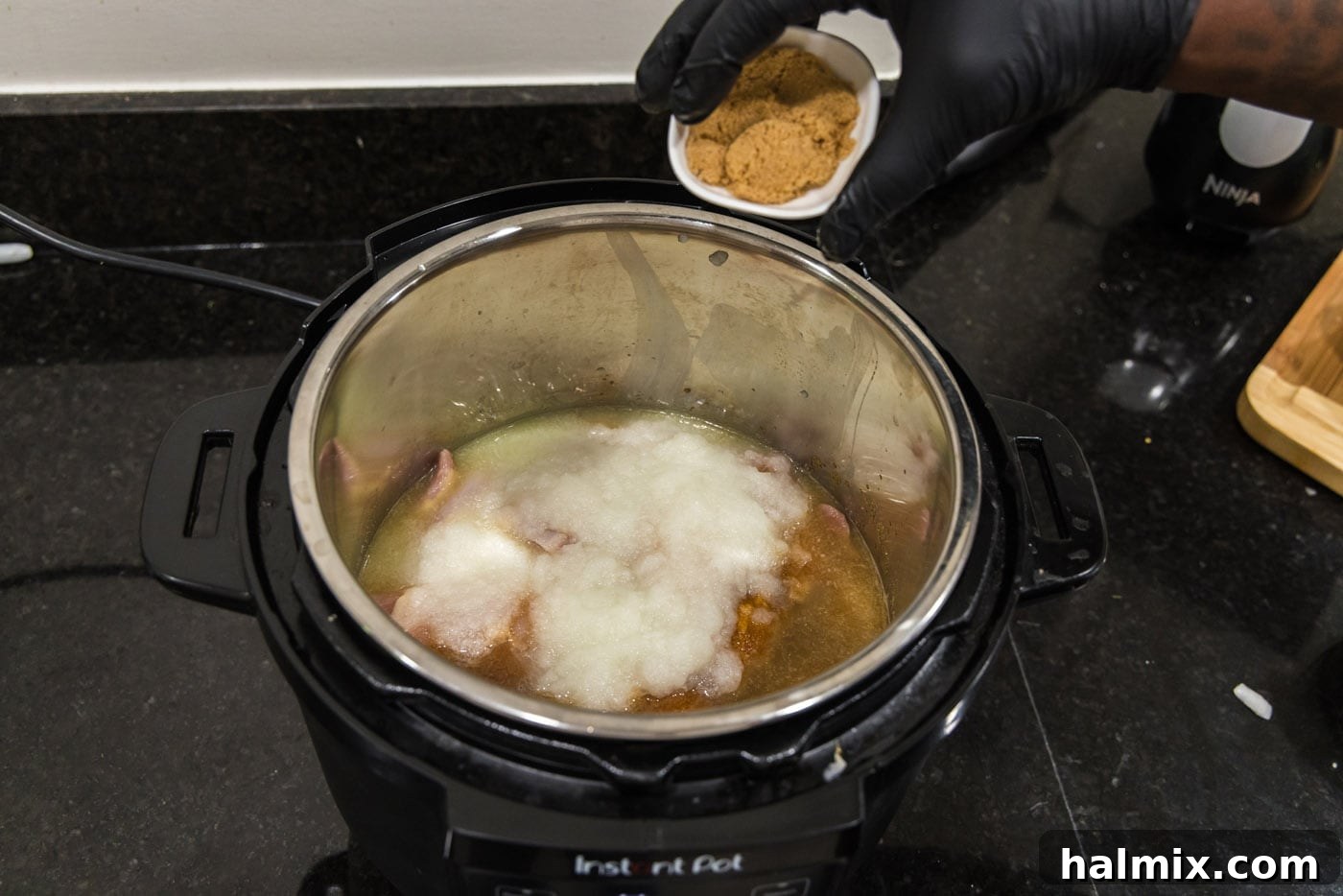 Adding brown sugar over the chicken and seasonings in the Instant Pot.