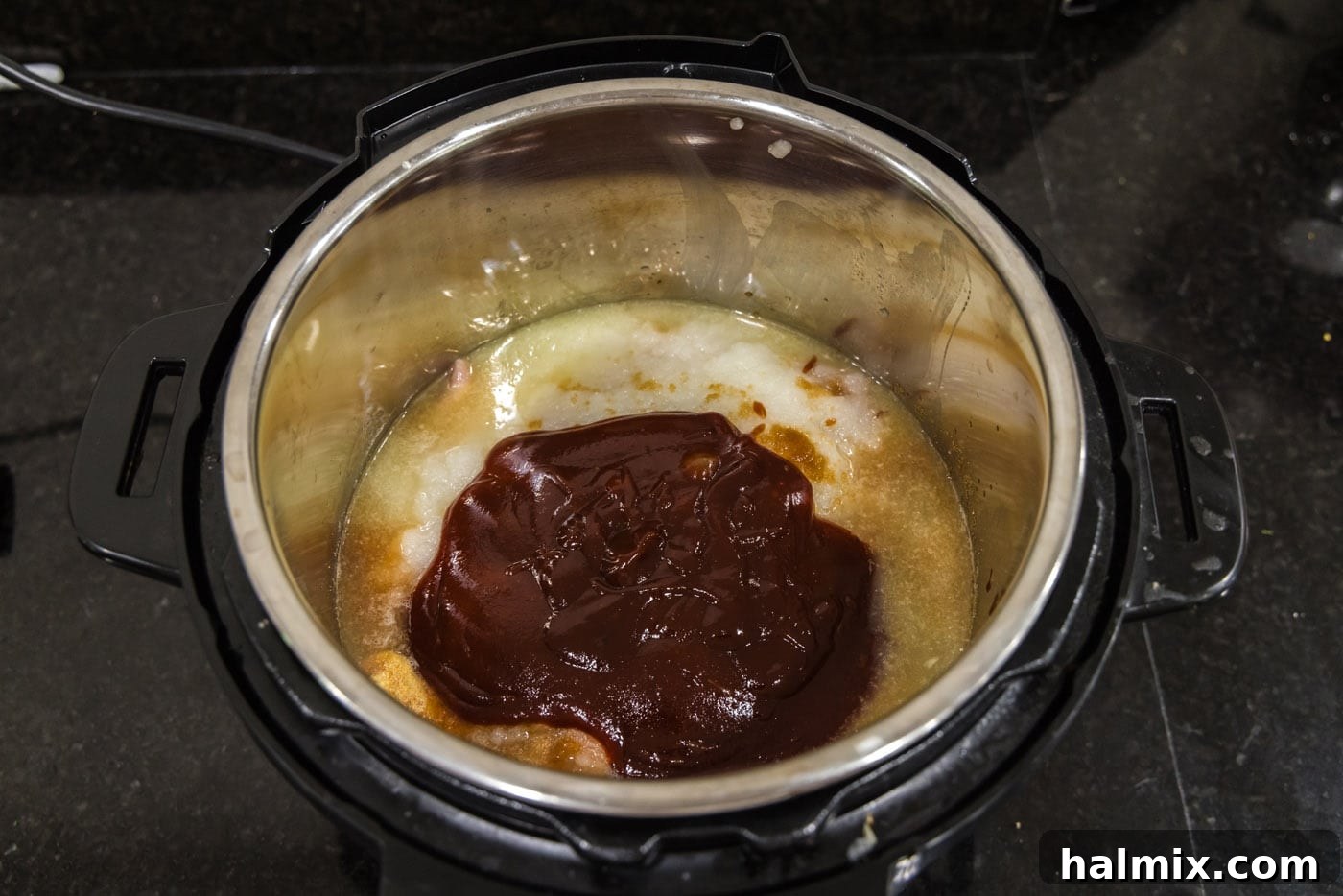 A thick layer of barbecue sauce covering the chicken and other ingredients in the Instant Pot.