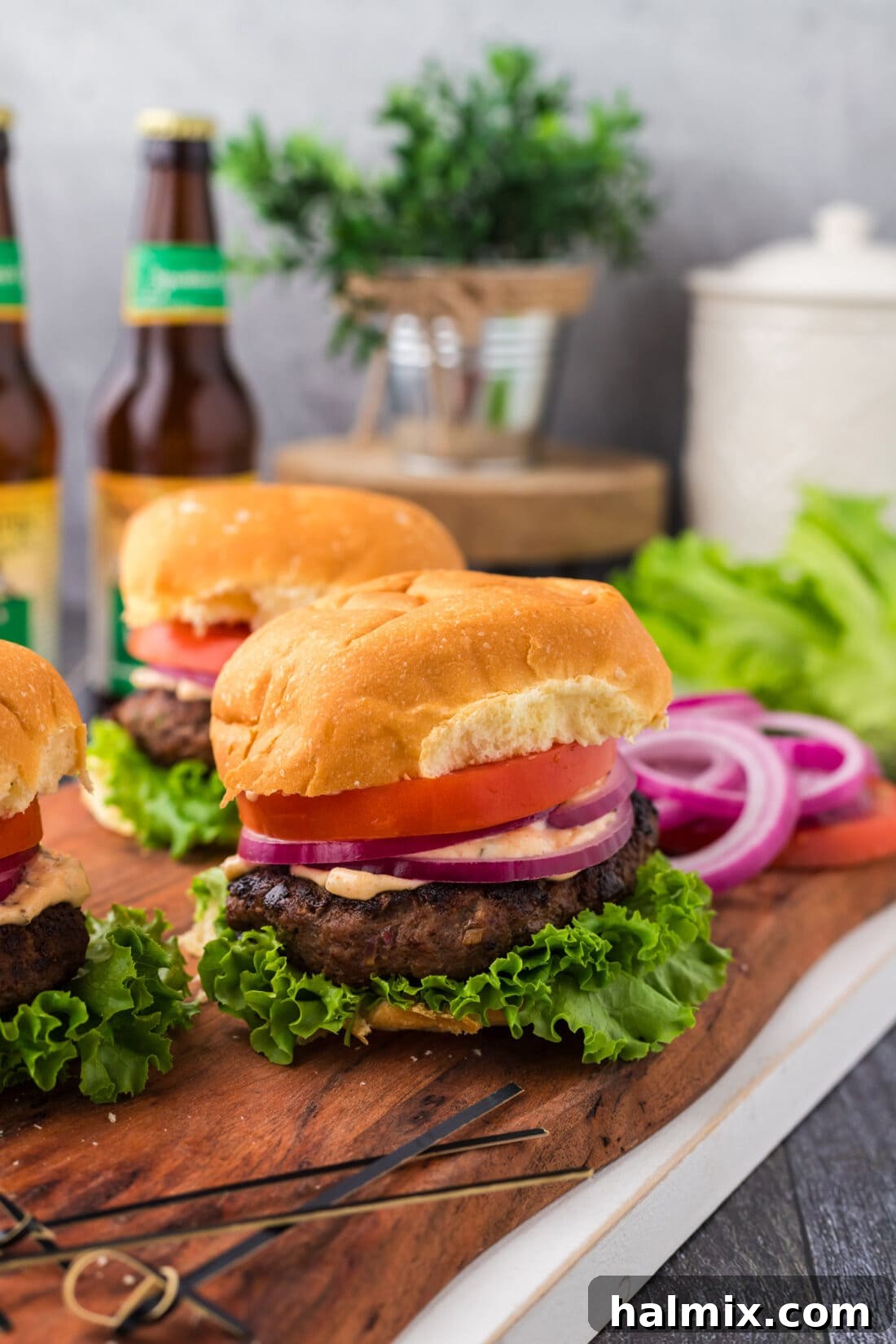 Mighty Buffalo Burger 2 Juicy Buffalo Burger on a rustic wooden board, with more burgers visible in the background, ready to be served.