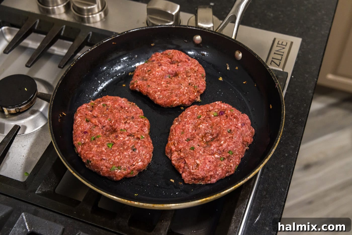 Mighty Buffalo Burger 10 Several bison burgers sizzling in a hot skillet, with a beautiful brown crust forming on their surface.