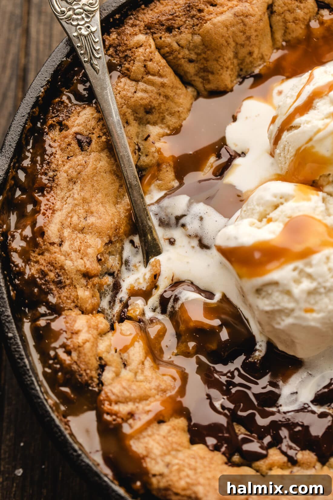 Decadent Caramel Chocolate Skillet 16 A spoon digging into a warm, gooey Chocolate Chip Caramel Skillet Cookie, showing melted chocolate and caramel.