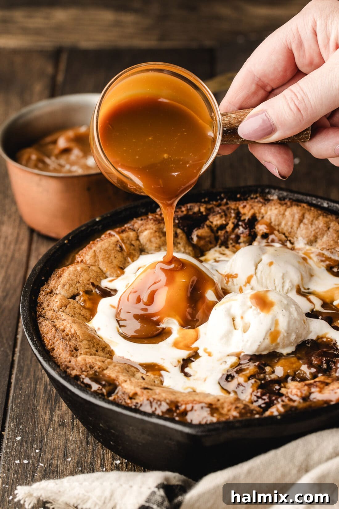 Decadent Caramel Chocolate Skillet 3 Warm salted caramel sauce being drizzled generously over a freshly baked Chocolate Chip Caramel Skillet Cookie.