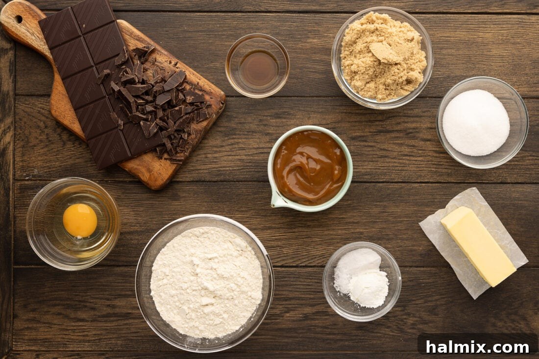 Decadent Caramel Chocolate Skillet 4 A collection of ingredients laid out, including flour, sugar, butter, eggs, chocolate, and a jar of caramel sauce, ready for making a skillet cookie.