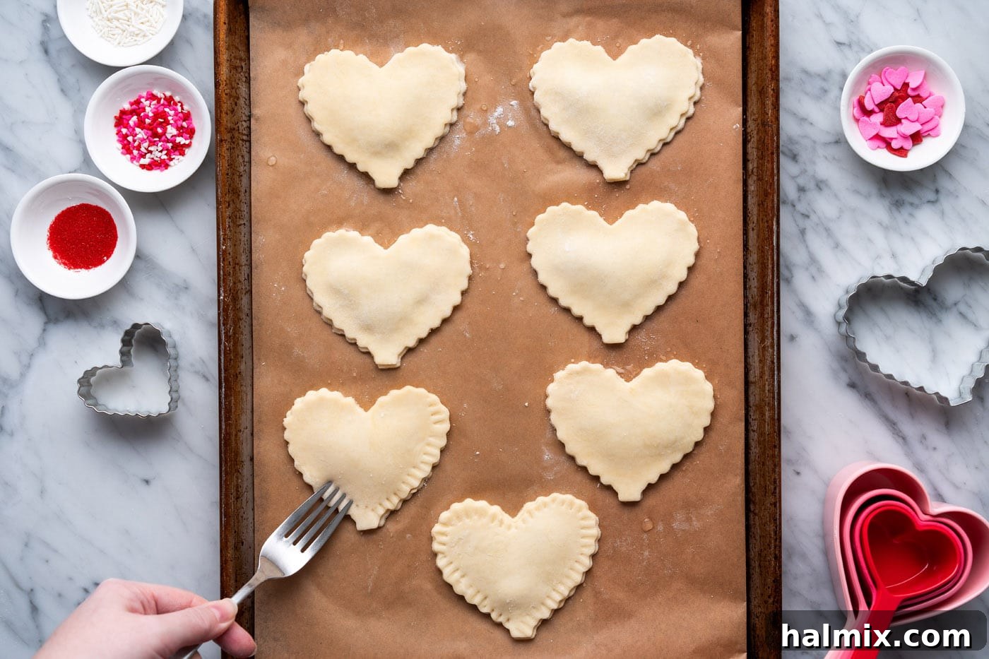 pressing edges of heart shaped pie dough with a fork