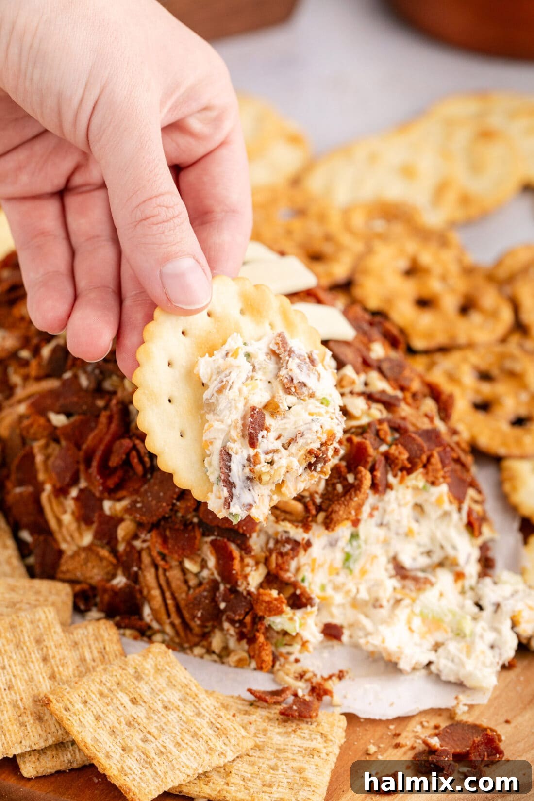 Hand holding a cracker with some cheese on it  from the Football Cheese Ball