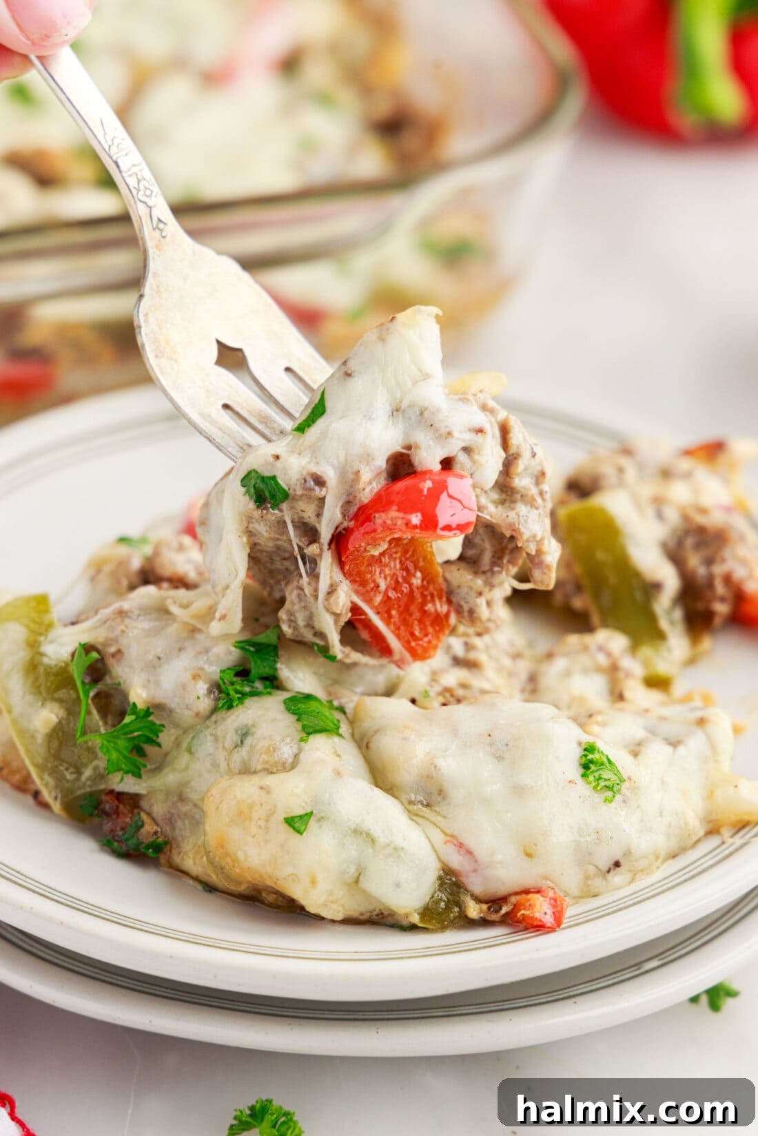 Forkful of Philly Cheesesteak Casserole being lifted off a plate of Philly Cheesesteak Casserole