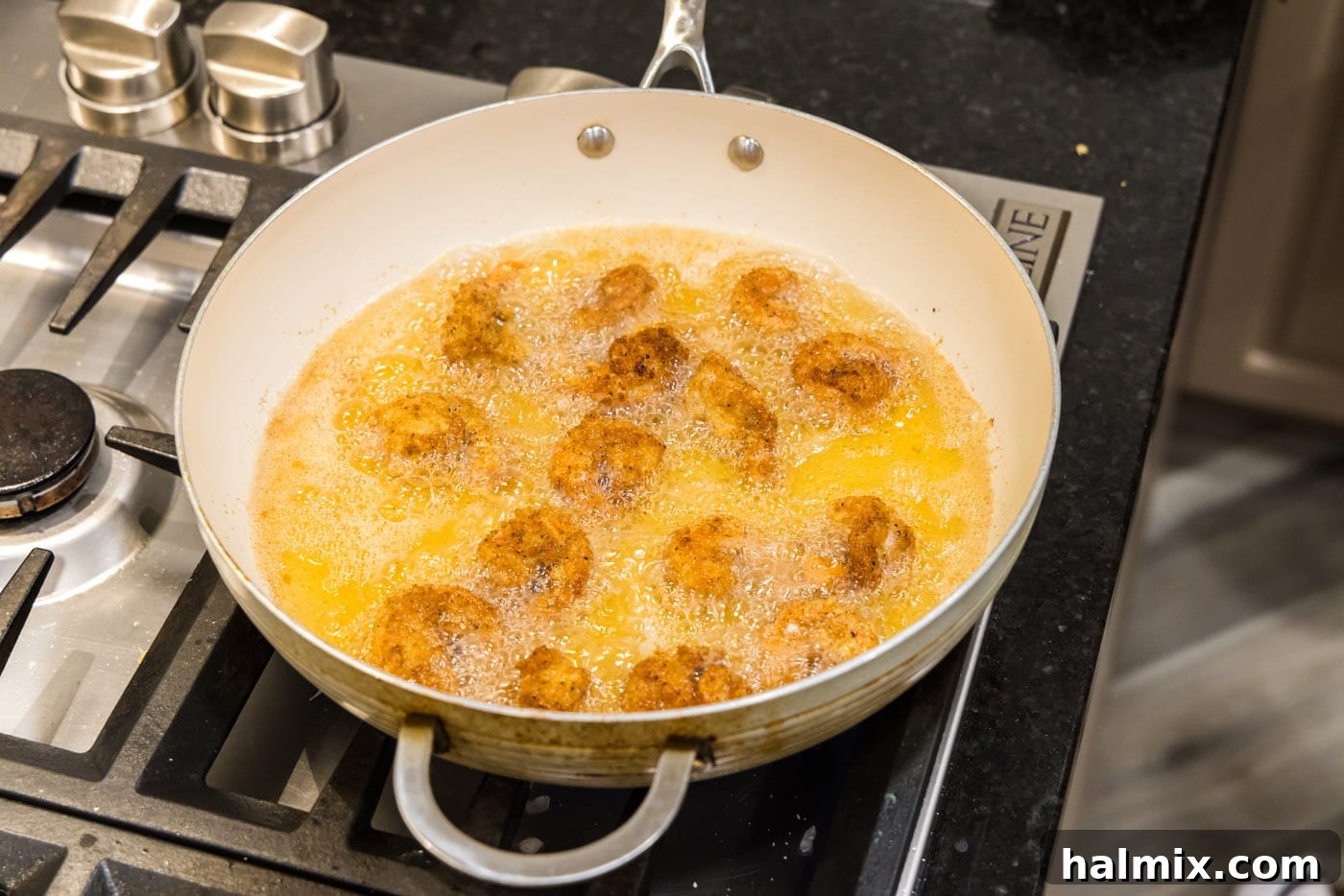 Breaded shrimp sizzling in hot oil in a skillet, turning golden brown