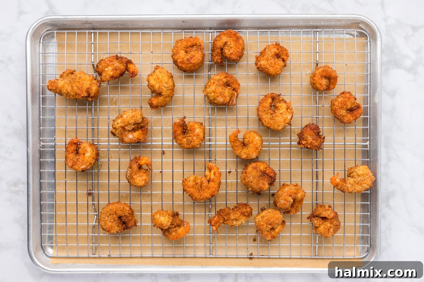 Golden fried breaded shrimp draining on a wire rack after cooking