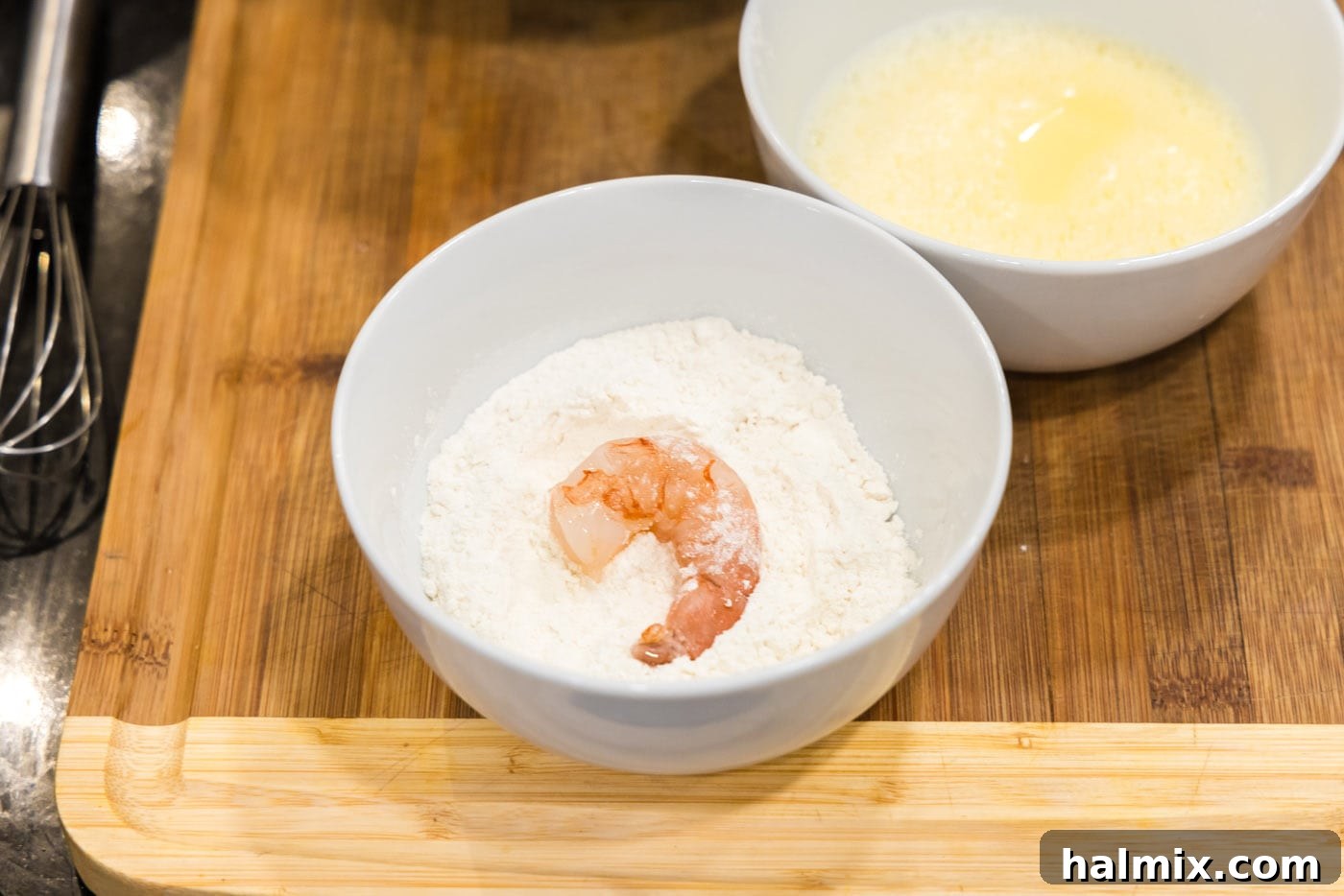 Shrimp being coated in flour, showing the first step of the breading process