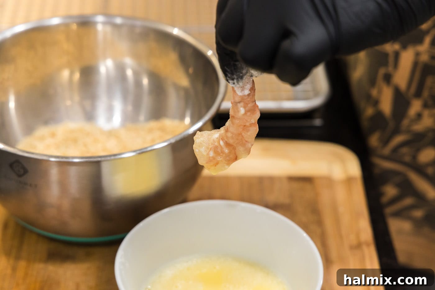 Flour-coated shrimp being dipped into the egg wash