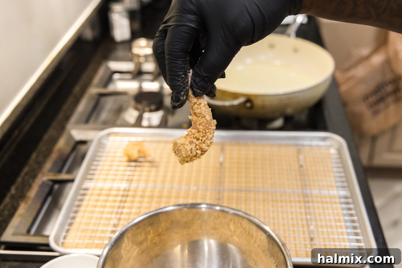 Hand holding a perfectly breaded shrimp, ready for frying