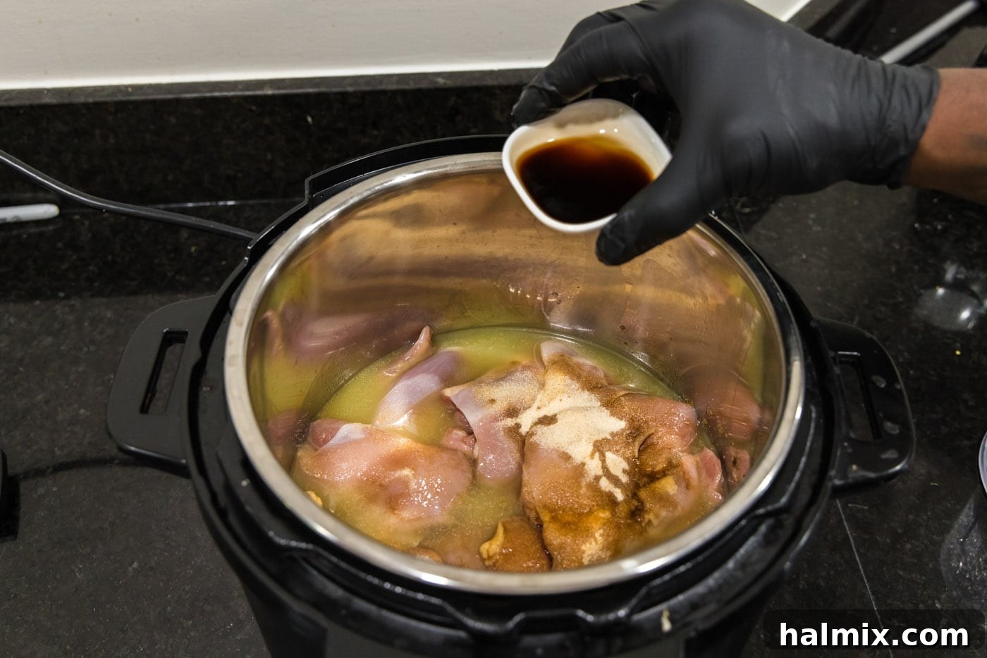 Adding Worcestershire sauce to the chicken in the Instant Pot.