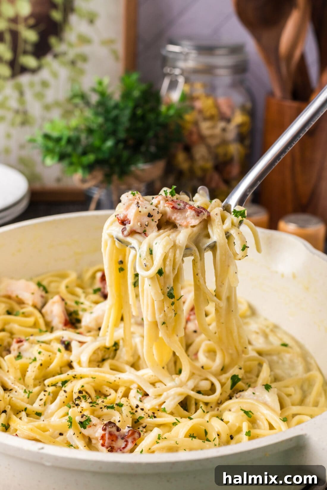 Spoonful of creamy lobster pasta being lifted from a skillet