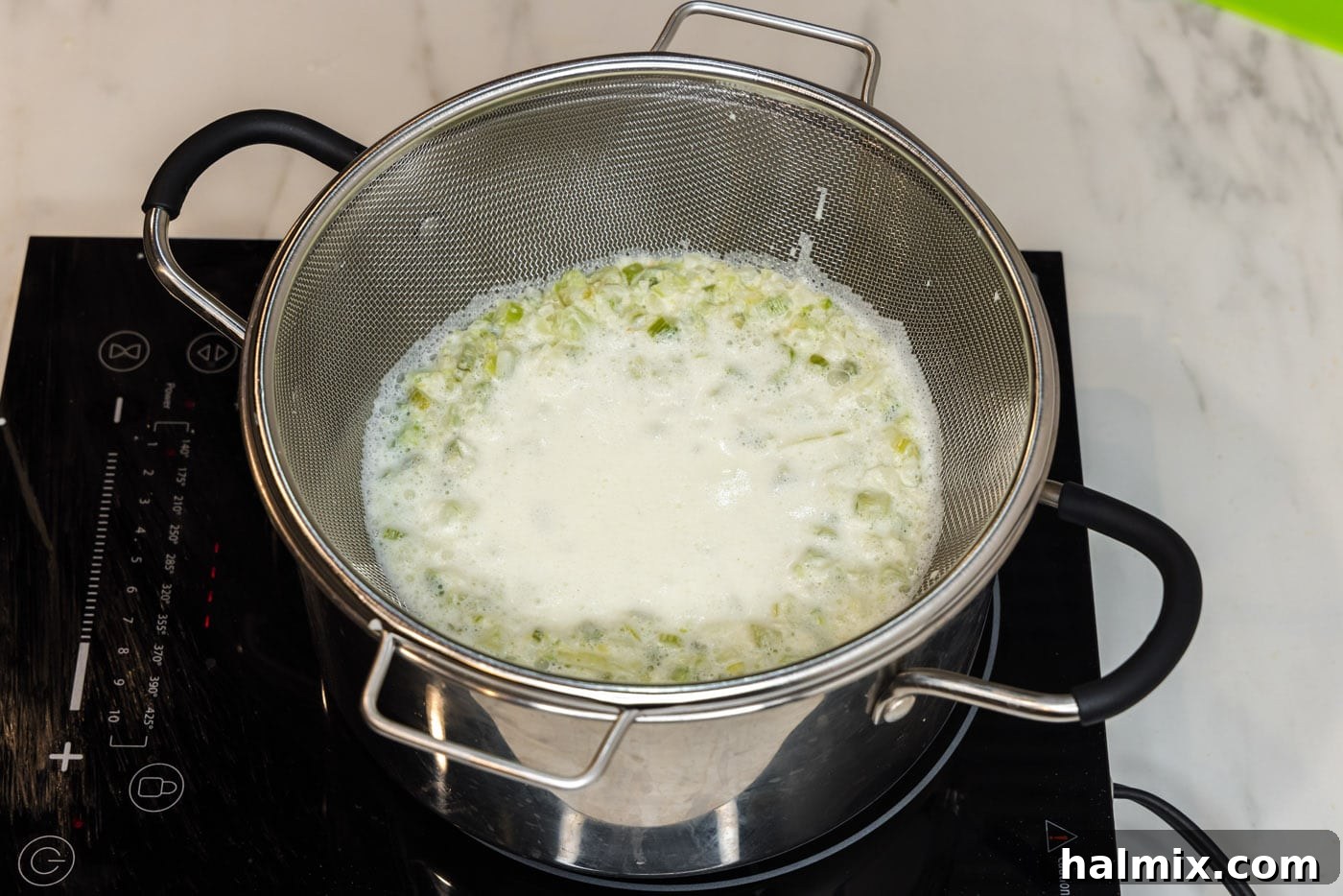 Straining creamy pasta sauce through a colander into a stockpot