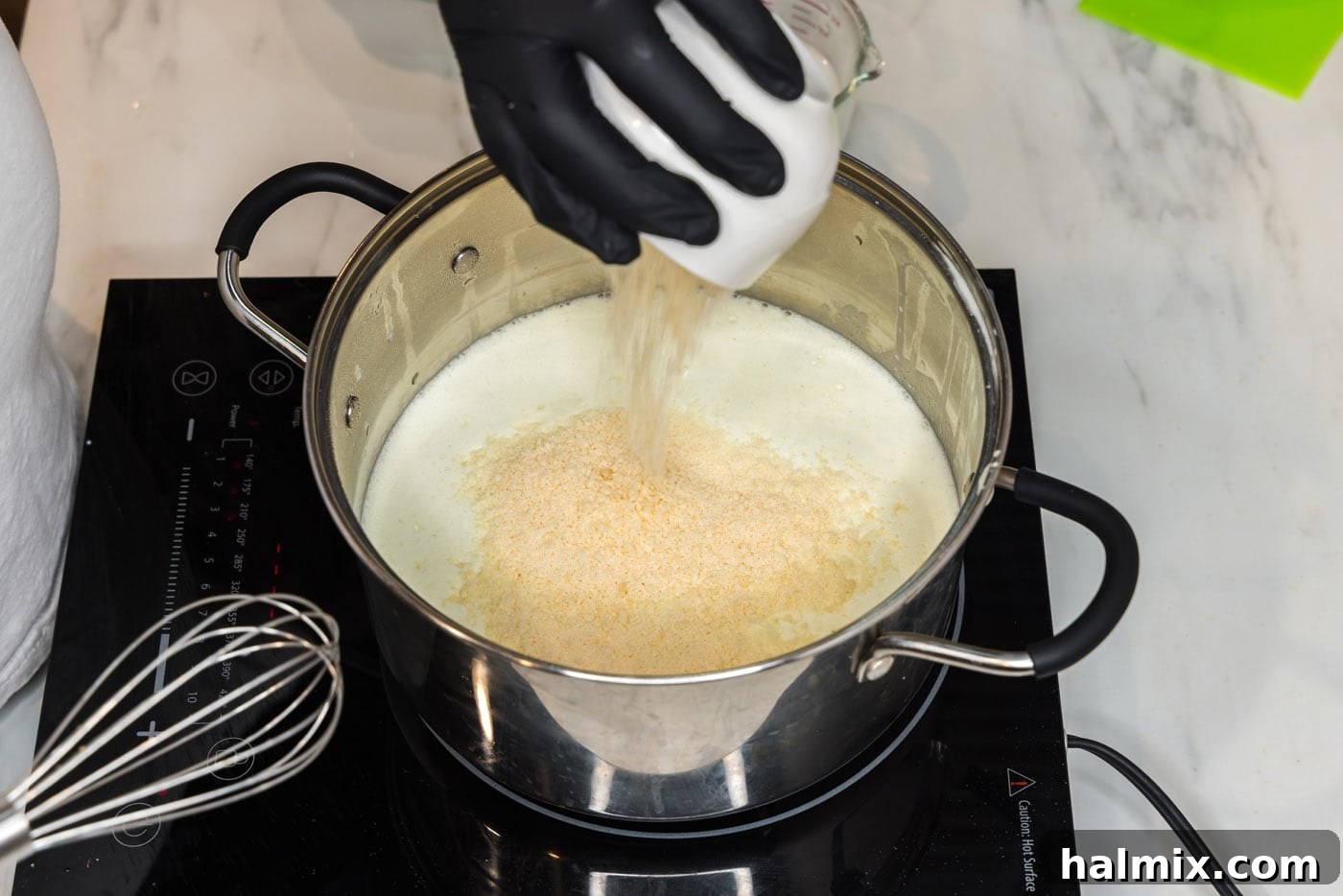 Pouring grated Parmesan cheese into the smooth sauce in a pot