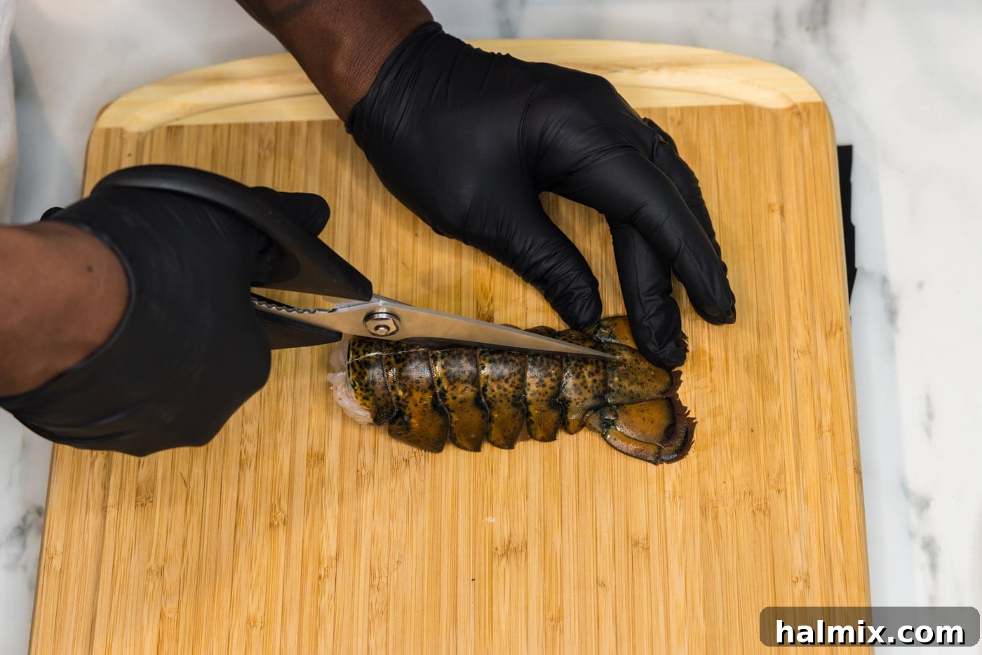 Kitchen shears slicing through lobster tail shell