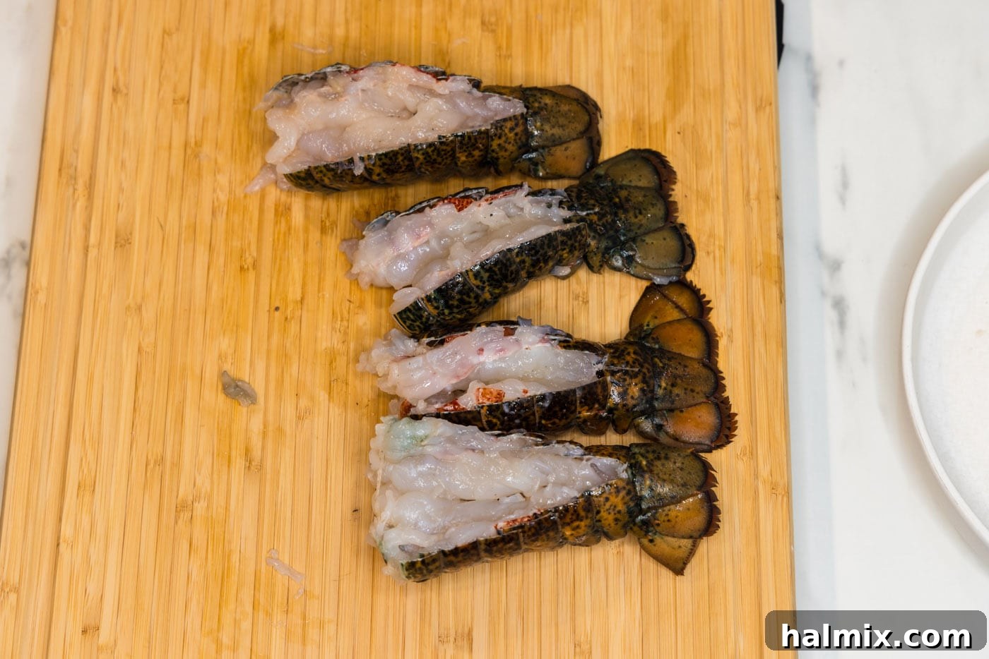 Raw lobster meat pulled out and resting on top of its opened shell