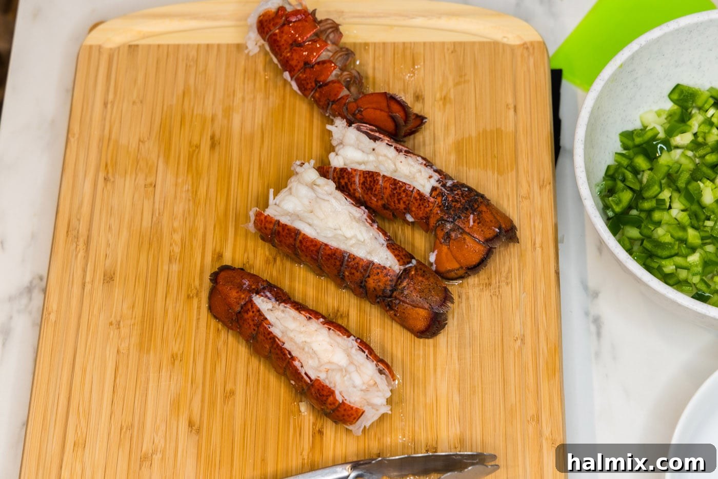 Cooked lobster tails resting on a cutting board, ready for meat removal